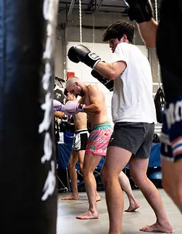 Students working the heavy bags during a striking class at Mission BJJ